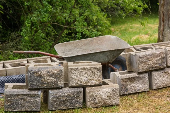 Schubkarre und Steine zum Bau einer Mauer